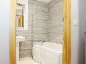 A bathroom with a bathtub, a sink, and a shower. - Gardener's Lodge (Nantwich)