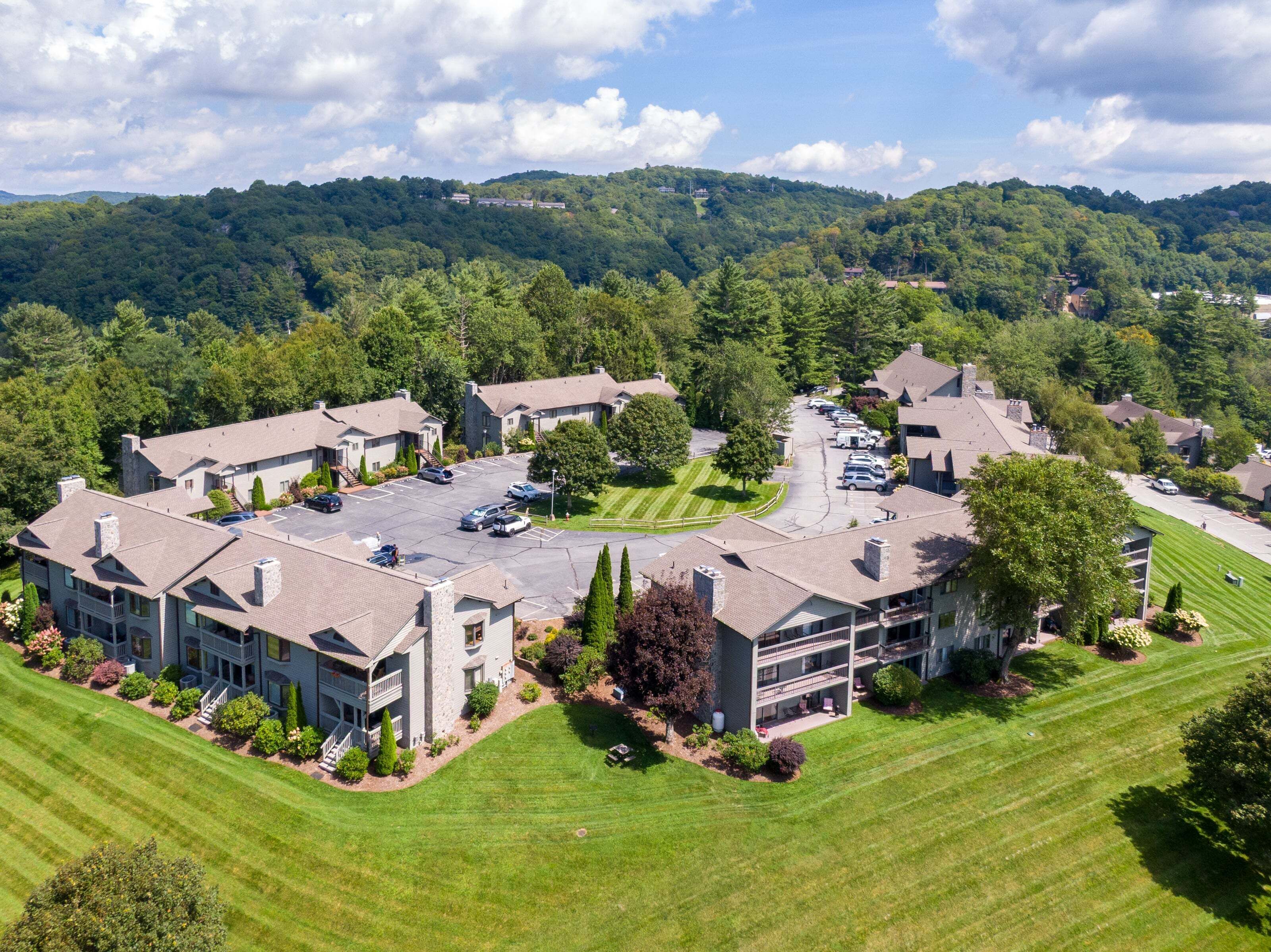 A residential area with multiple two-story houses, a parking lot, and a well-maintained lawn.