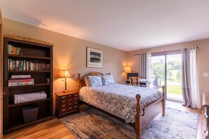 Ein Schlafzimmer mit einem Bett, einem Bücherregal, einem Schreibtisch und einem Fenster mit Vorhängen.