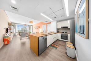 A modern kitchen with a dishwasher, oven, and a dining area with a table and chairs. - Stayshort - Comfortable 1BR Apartment in JVT With Gym Pool Sleeps 2 (Dubai)