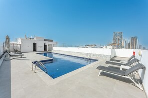A rooftop pool with lounge chairs, a satellite dish, and a view of the city skyline. - Stayshort - Comfortable 1BR Apartment in JVT With Gym Pool Sleeps 2 (Dubai)