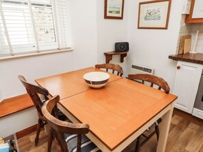 Ein Holzespeisesaal mit Stühlen, einer Schüssel, einem kleinen Tisch mit einem Radio und gerahmten Bildern an der Wand.