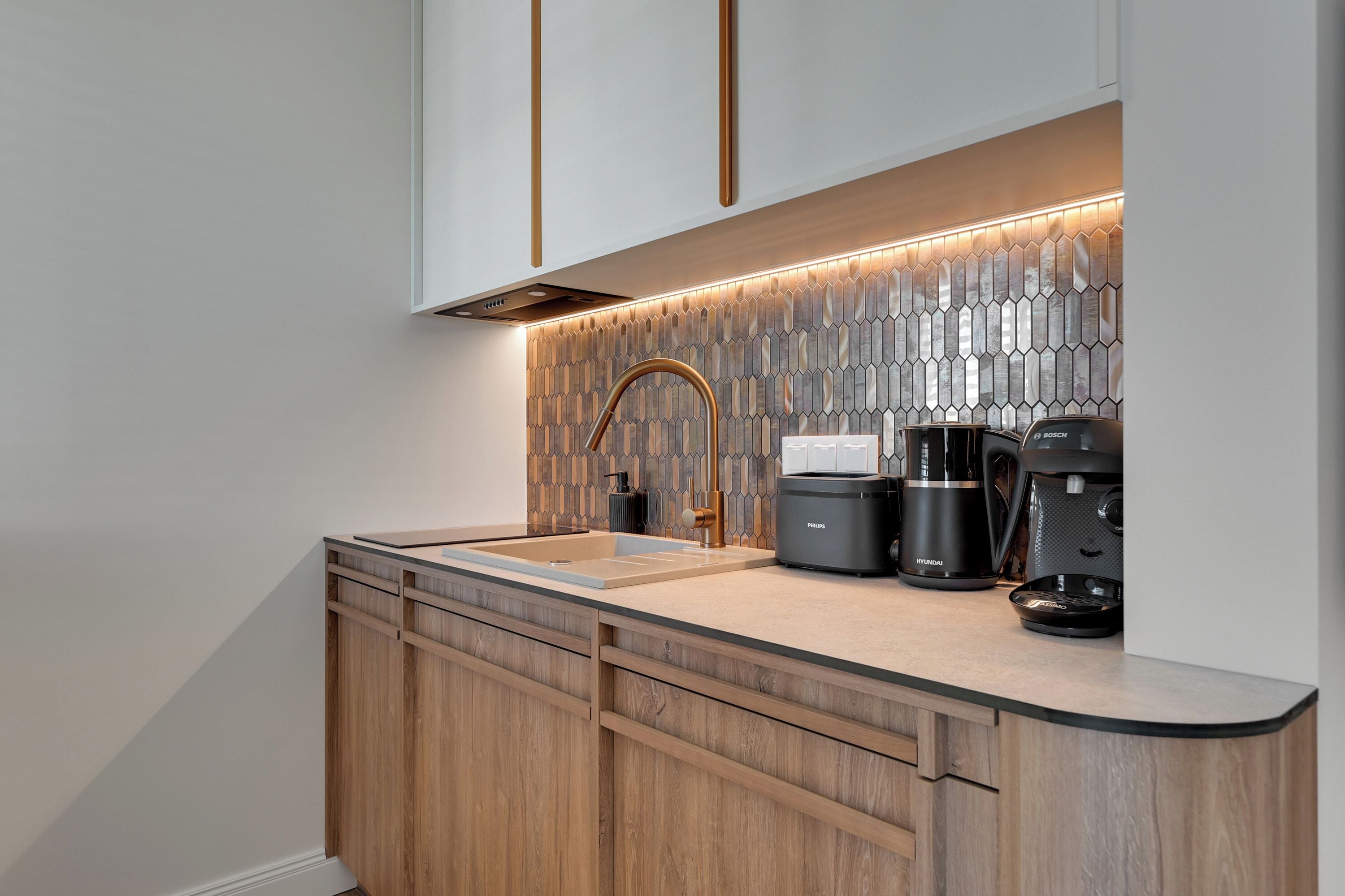 A modern kitchen with a wooden cabinet, a stainless steel sink, and a coffee maker.