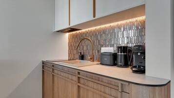 A modern kitchen with a wooden cabinet, a stainless steel sink, and a coffee maker.