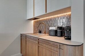A modern kitchen with a wooden cabinet, a stainless steel sink, and a coffee maker. - Perspektywa Apartment with balcony (Gdańsk)