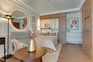 Un dormitorio moderno con cama, mesitas de noche, un espejo redondo y obras de arte en las paredes.