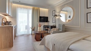 Ein modernes Schlafzimmer mit einem großen Bett, einem Schreibtisch, einem Sessel, einem runden Spiegel und einem Fernseher.