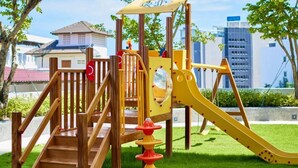 Un parque infantil con escalones de madera, un tobogán y una estructura para escalar.