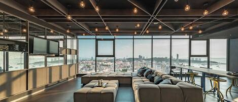 Un salón moderno con un sofá grande, un televisor de pantalla plana y vistas a la ciudad.