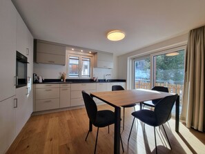 A modern kitchen with white cabinets, a wooden dining table, and black chairs. - Haus Rio Appartement/Fewo Appartement/Fewo by Interhome (Saas-Fee)