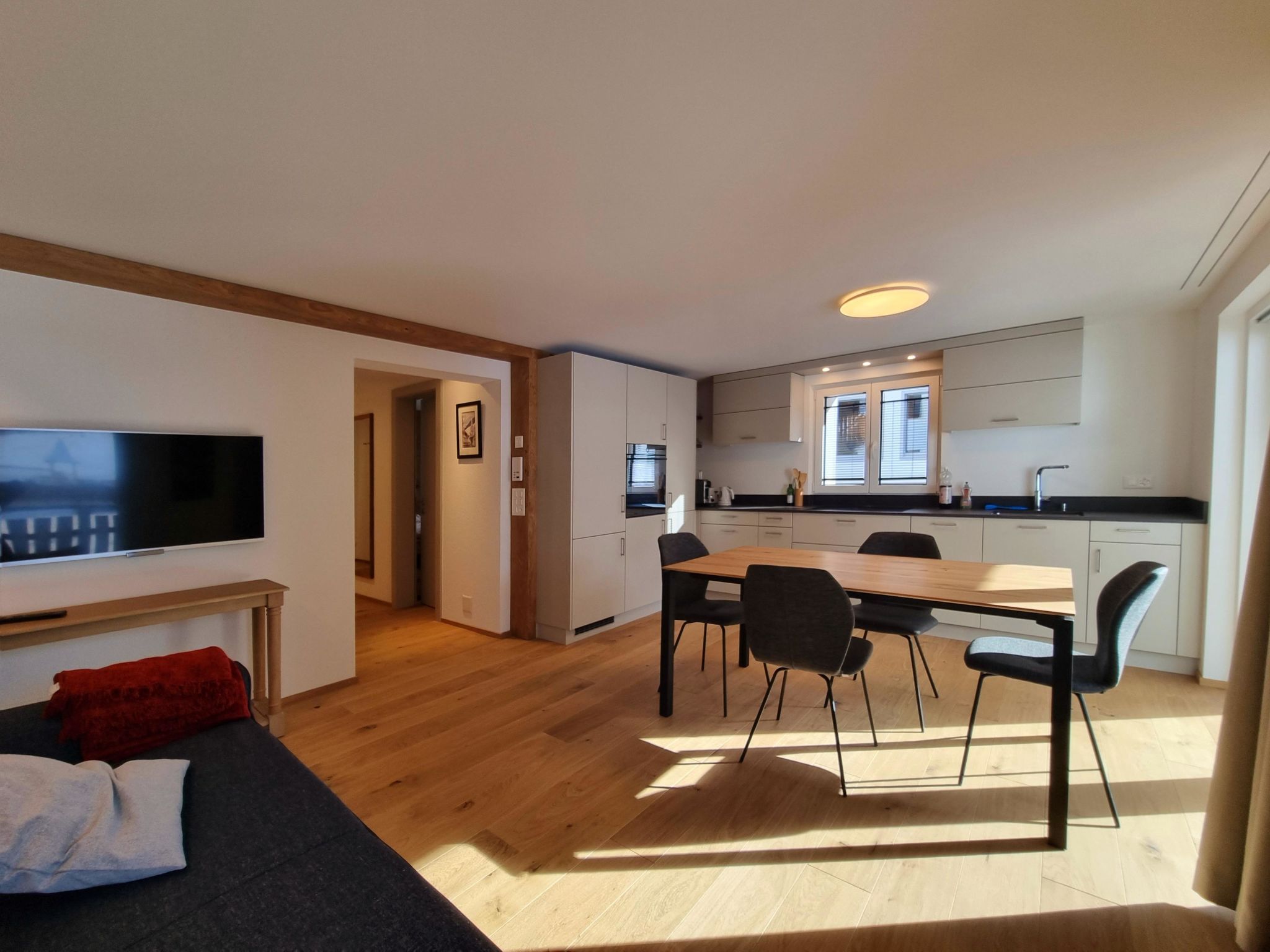 A modern apartment with a living room, dining area, and kitchen.