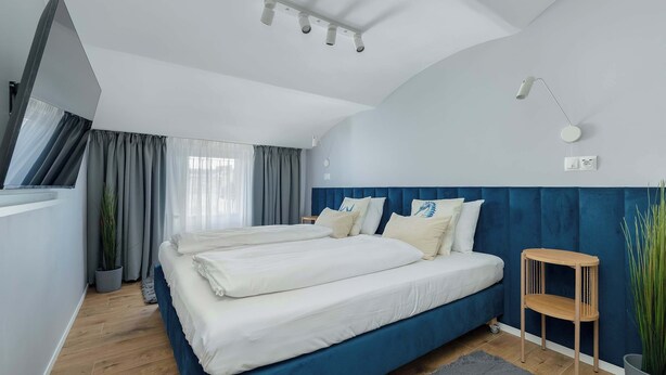 Un dormitorio moderno con una cama grande, una mesita de noche, una lámpara y una planta en maceta.
