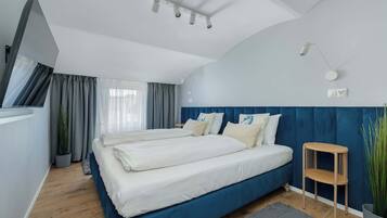 Ein modernes Schlafzimmer mit einem großen Bett, einem Nachttisch, einer Lampe und einer Topfpflanze.