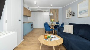 Una sala de estar moderna con un sofá azul, una mesa de centro redonda de madera y un comedor con sillas azules.
