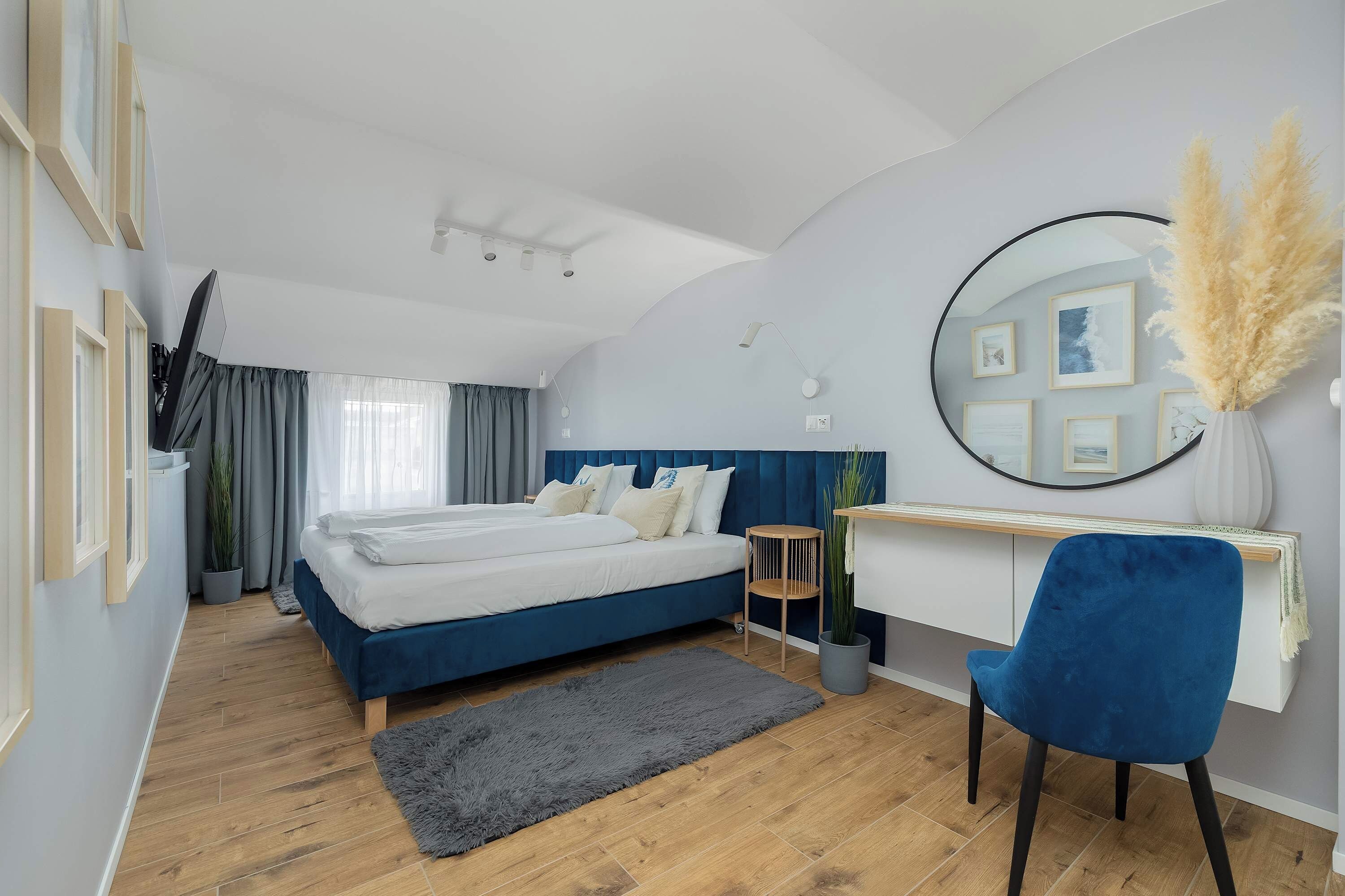 Ein modernes Schlafzimmer mit Bett, Schreibtisch, Stuhl und einem großen Spiegel.