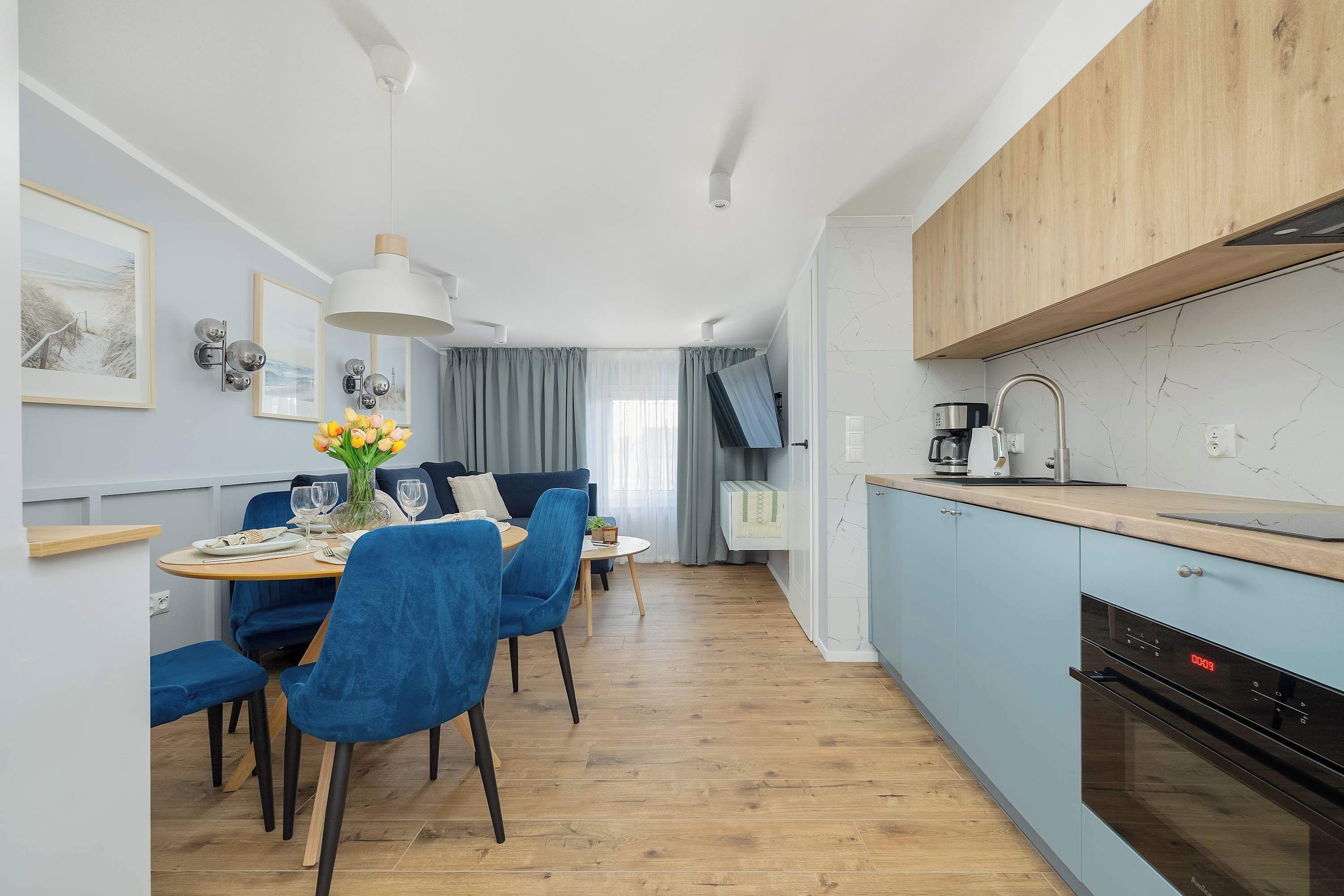 Eine moderne Küche mit Backofen und einem Essbereich mit blauen Stühlen und einem runden Tisch.