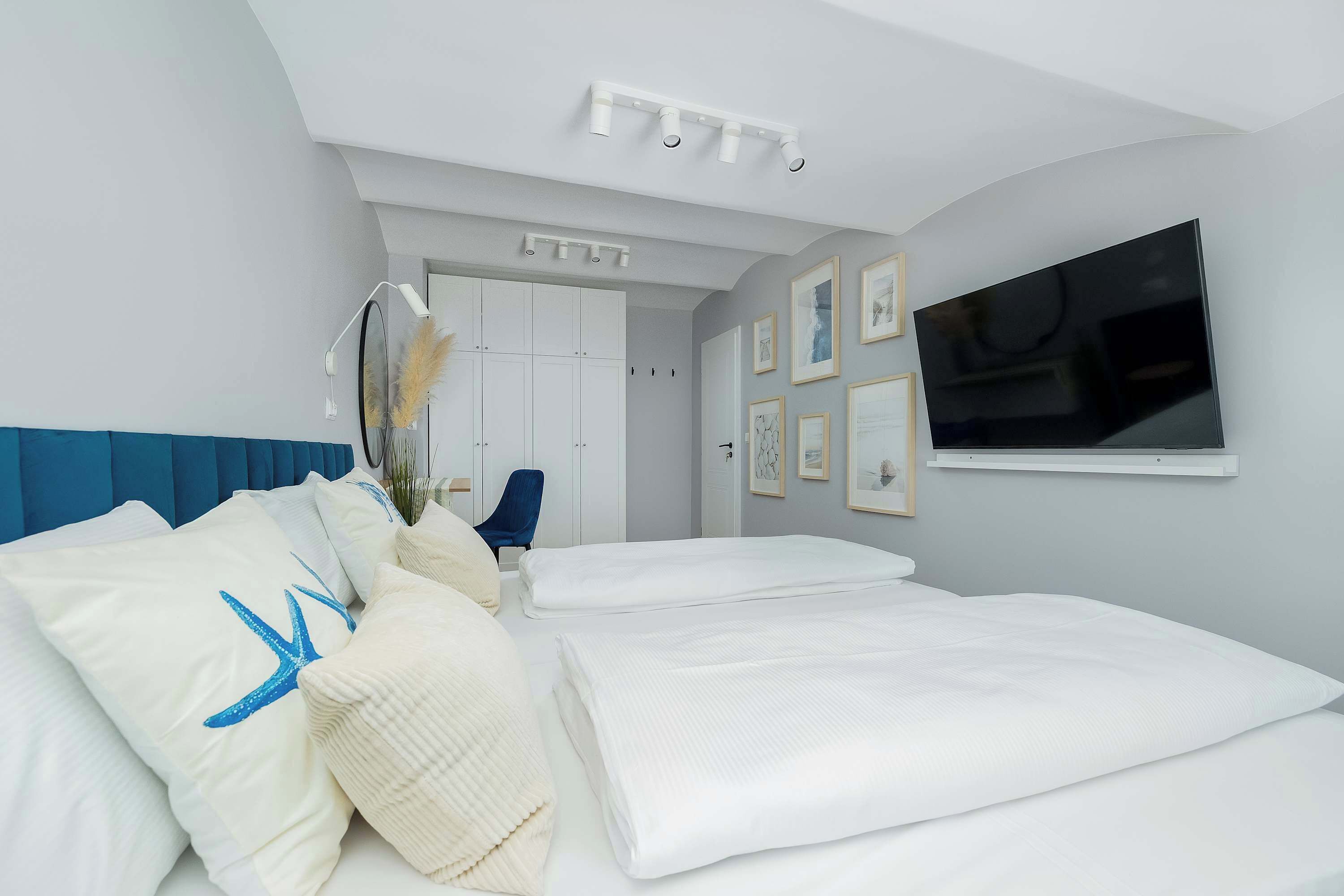 Ein Schlafzimmer mit einem Bett, einem an der Wand montierten Fernseher und einer Deckenleuchte.