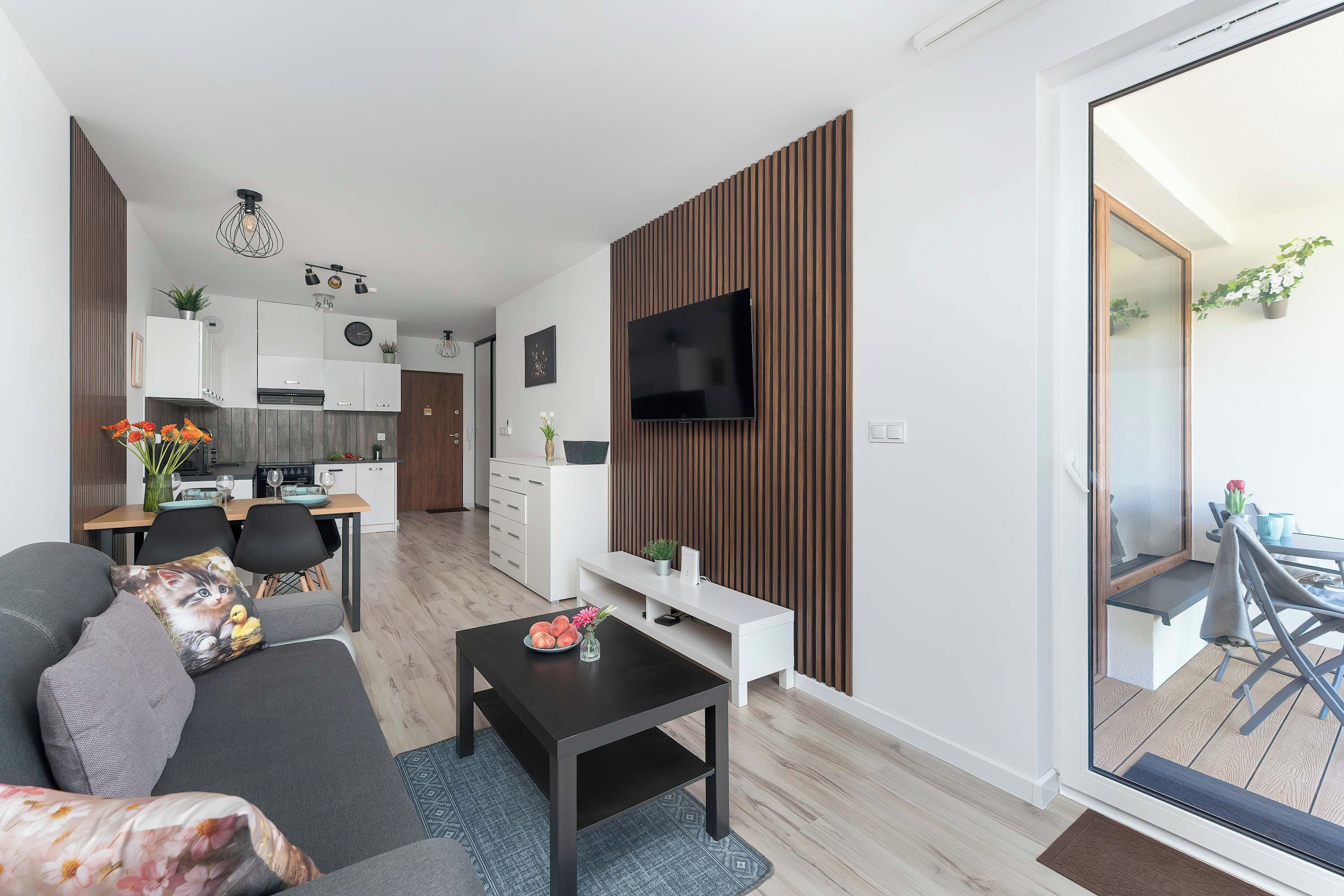Een moderne woonkamer met een bank, salontafel en een flatscreen televisie aan de wand.