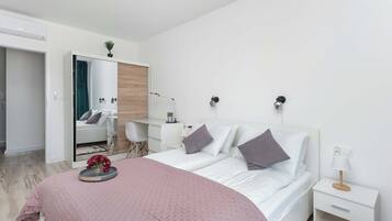 Een moderne slaapkamer met een bed, nachtkastjes, een bureau en een spiegel.