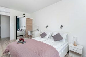 A modern bedroom with a bed, bedside tables, a desk, and a mirror. - Air Conditioned Apartment with Balcony | Parking (Mielno)