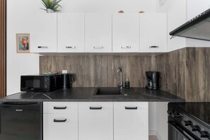 A modern kitchen with white cabinets, a black countertop, and a built-in oven. - Air Conditioned Apartment with Balcony | Parking (Mielno)