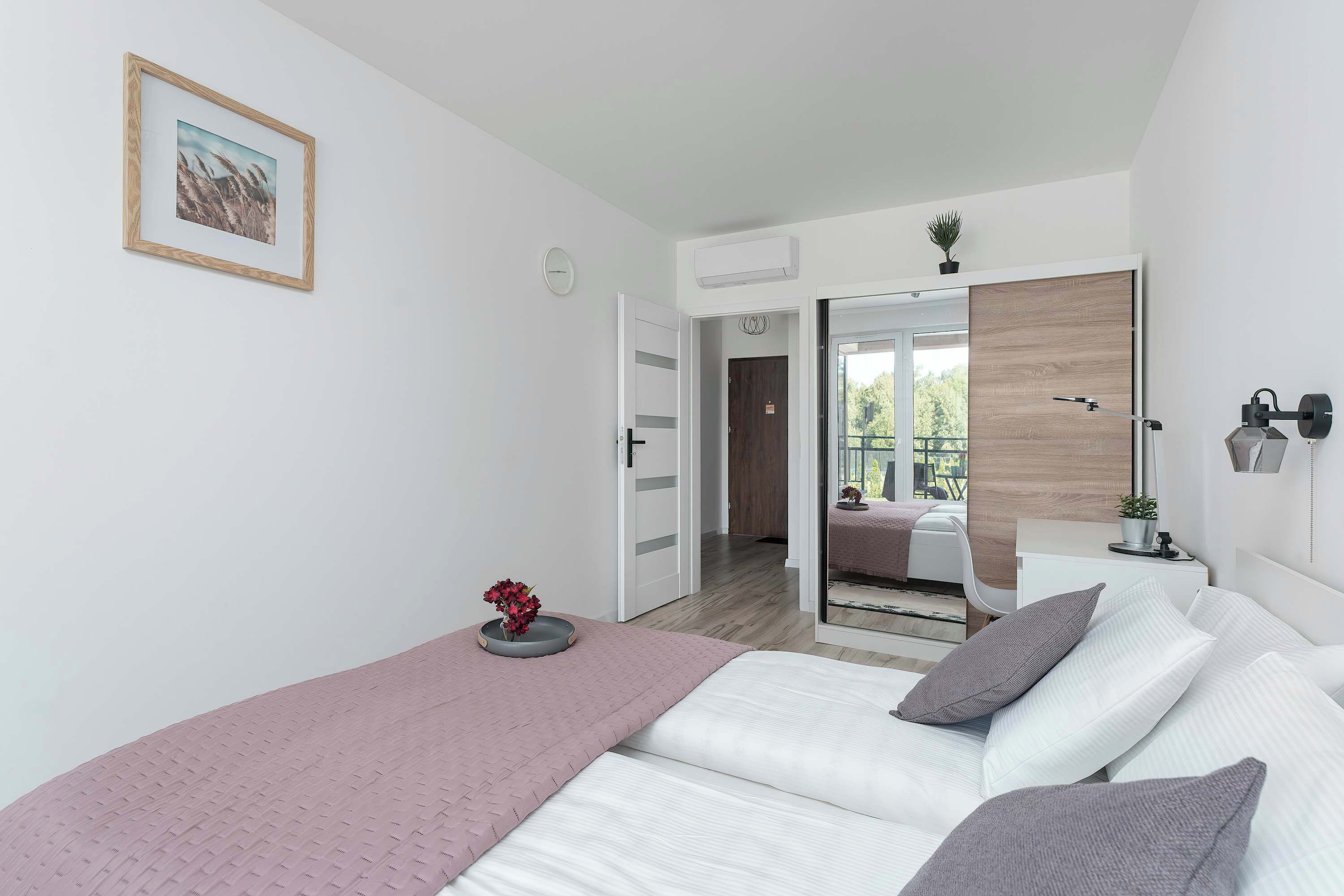 A modern bedroom with a bed, bedside table, and a mirror.