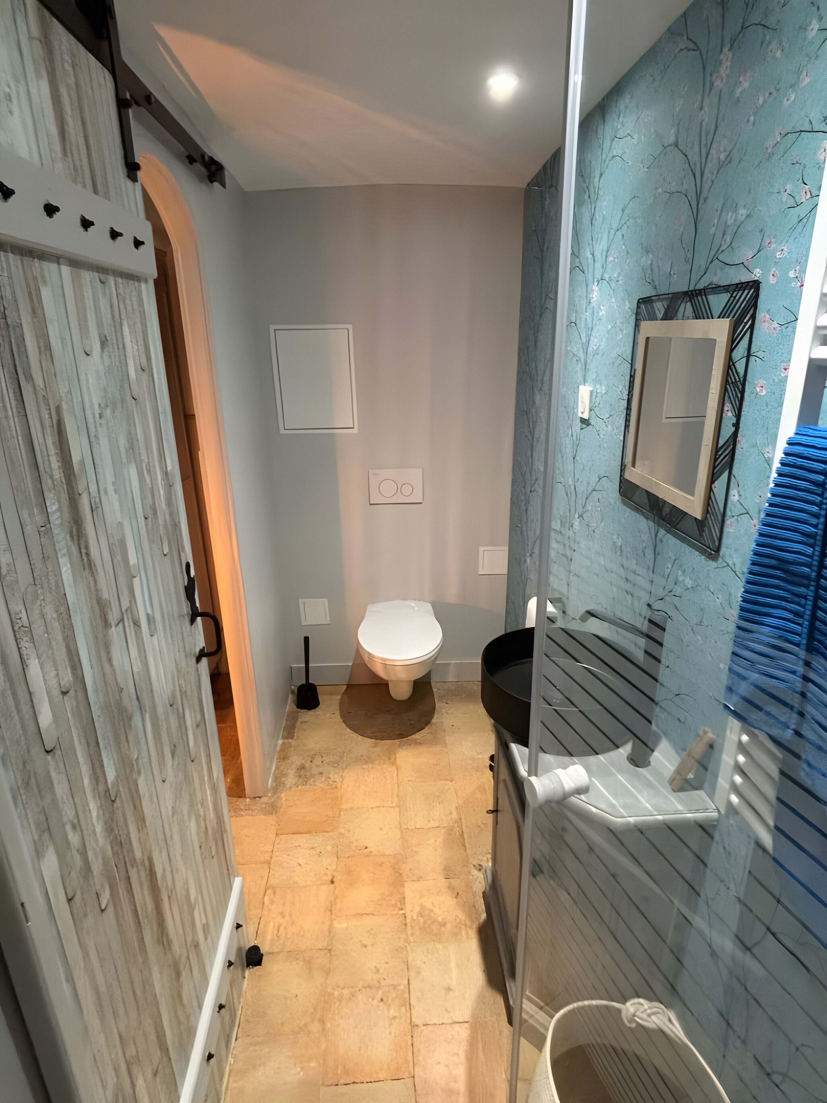 Et badeværelse med toilet, bidet, vask og et spejl på væggen.