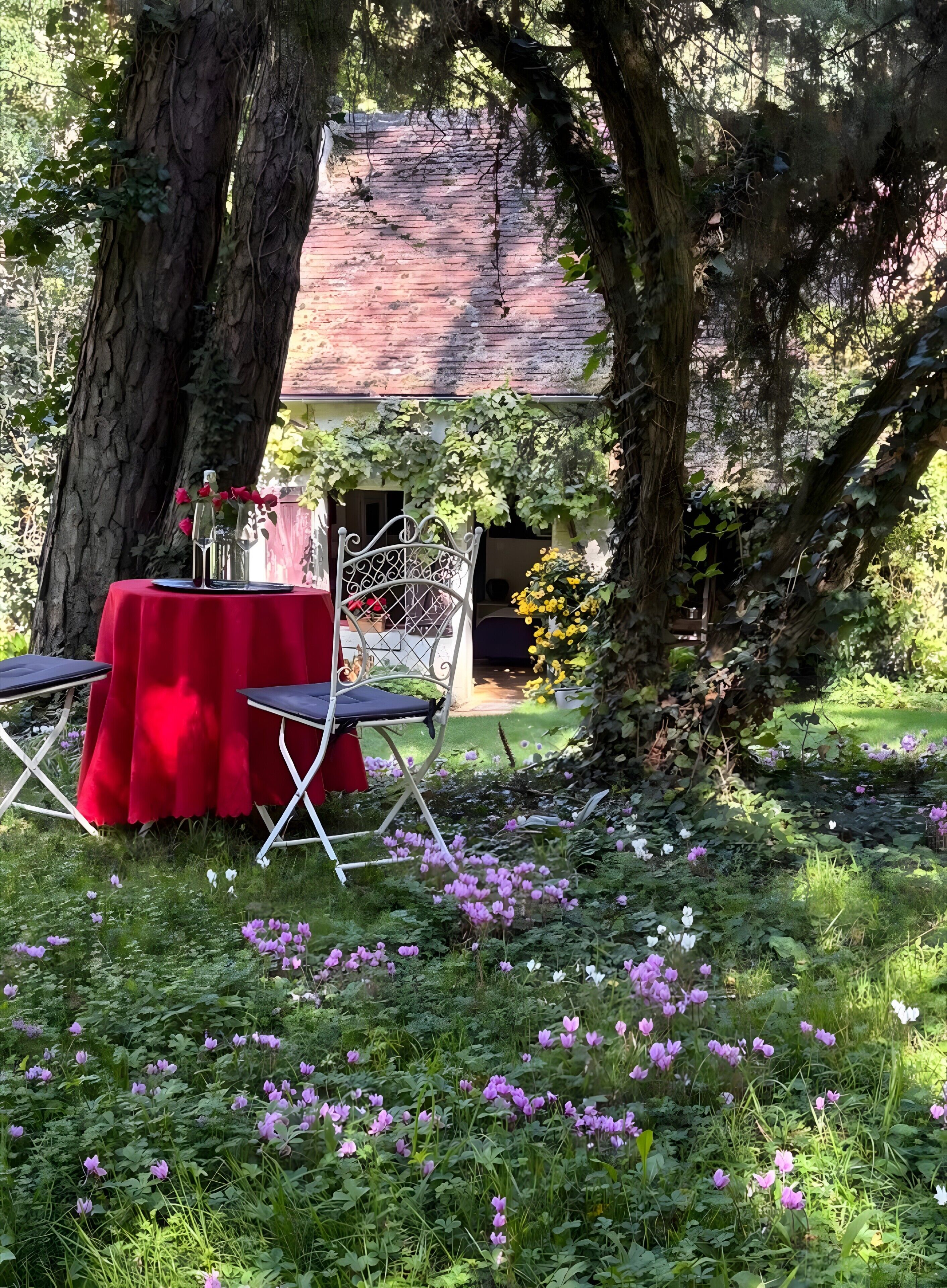 An outdoor dining area with a red tablecloth, two chairs, and a white metal chair.