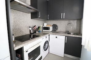 A compact kitchen with a built-in oven, microwave, sink, and a washing machine. - Winter Sun & Golf Estepona: Long-Stay Oasis (Estepona)