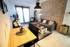 A modern living room with a sofa, a dining table with chairs, a coffee table, and a hanging lamp. - Winter Sun & Golf Estepona: Long-Stay Oasis (Estepona)