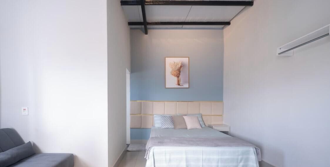 A bedroom with a bed, a bedside table, a chair, and a wall-mounted artwork.