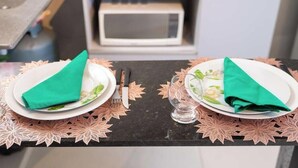 To tallerkener med foldede servietter på et bord med en dekorativ dug med bladmotiv.