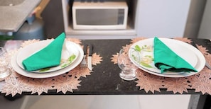 Two plates with folded napkins on a table with a decorative leaf-patterned placemat. - Flat em Uberlandia Proximo ao Parque Gavea (Uberlândia)