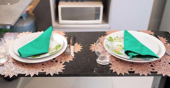 Two plates with folded napkins on a table with a decorative leaf-patterned placemat.