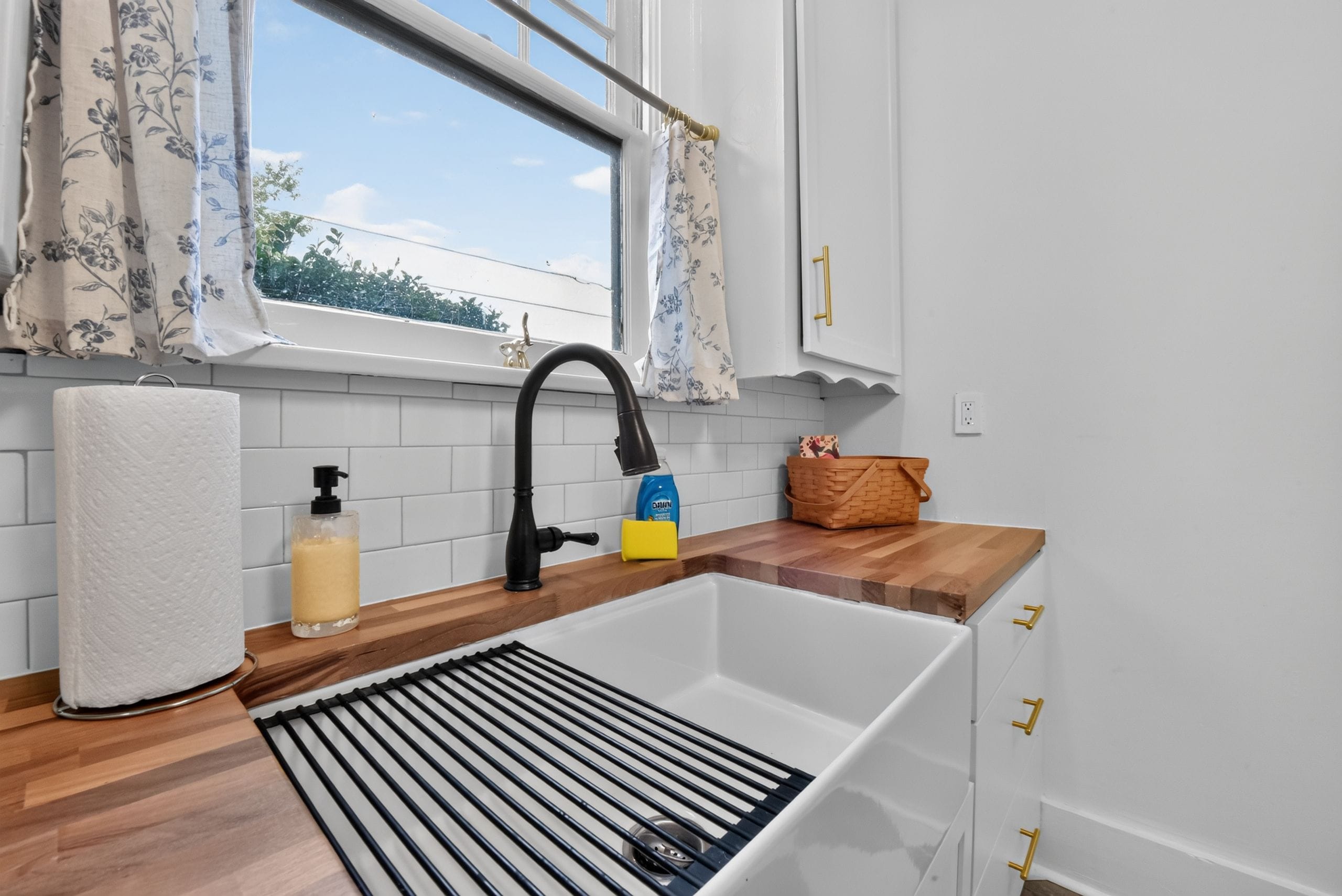 Eine Küche mit einer weißen Spüle, einem schwarzen Wasserhahn und einer Holzausziehtafel.