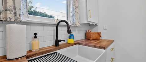 Eine Küche mit einer weißen Spüle, einem schwarzen Wasserhahn und einer Holzausziehtafel.