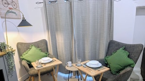 Una habitación pequeña y acogedora con dos sillones, una mesita y una lámpara de pie.