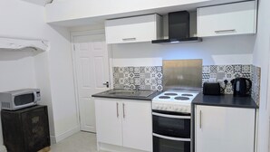 Una cocina funcional con armarios blancos, microondas, estufa y tostadora.