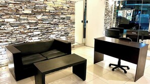 A modern interior with a stone wall, a black leather sofa, a wooden desk, and a glass door leading to a car. - Bright Studio Apartment in the Heart of Palermo (Buenos Aires)