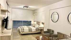 A modern bedroom with a bed, bedside tables, a chair, and a dining area with chairs. - Bright Studio Apartment in the Heart of Palermo (Buenos Aires)