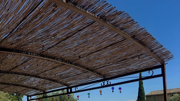 Uima-altaan reunalla oleva alue, jossa on aurinkotuoleja ja pergola.