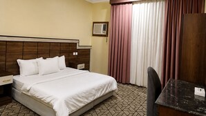 A hotel room with a bed, a desk, a chair, a wardrobe, and a window with curtains. - OrbitNet HJ (Madinah)