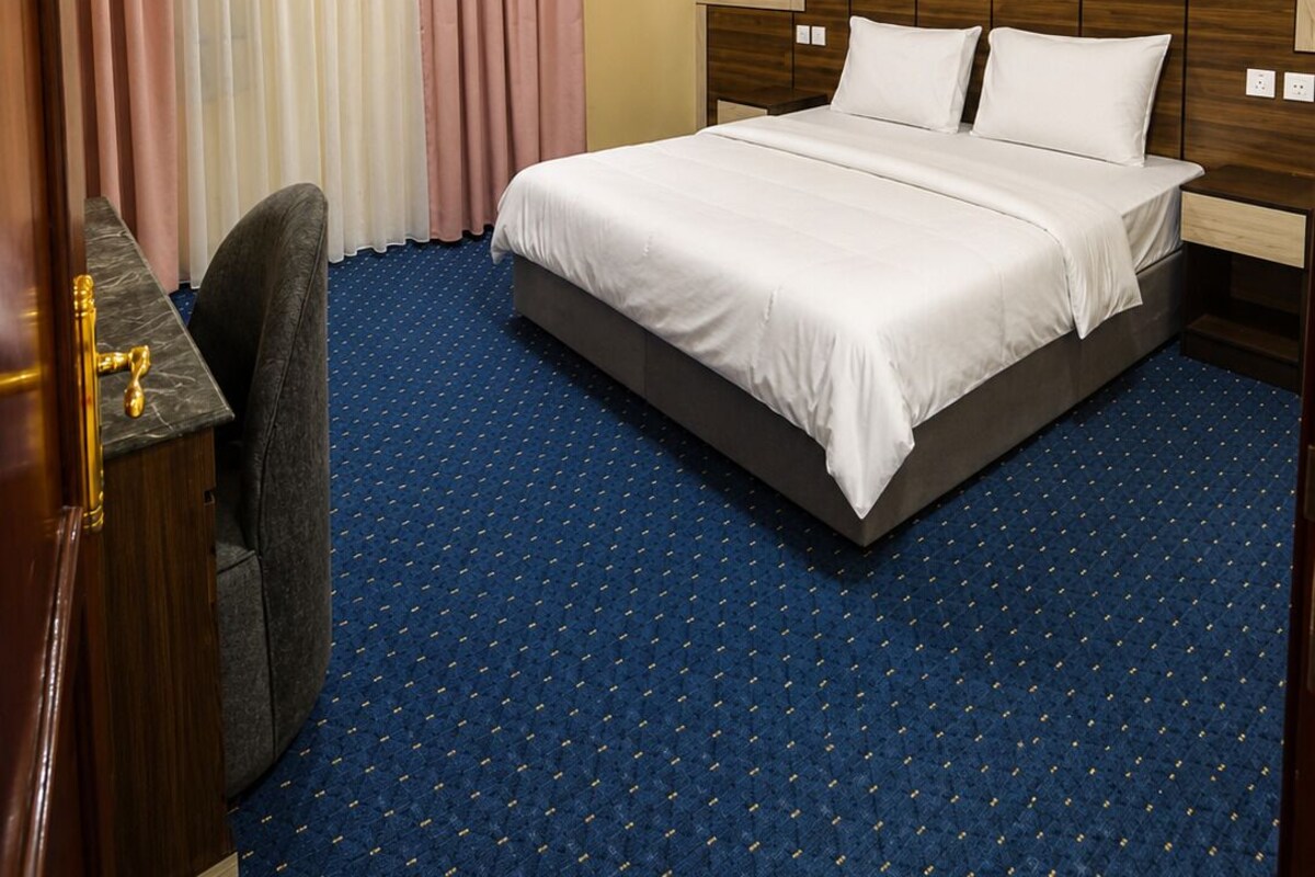 Habitació d'hotel amb un llit, una taula de treball, una cadira, una finestra amb cortines i un aparell d'aire condicionat.