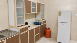 A kitchen with a gas stove, a sink, and a refrigerator. - OrbitNet HJ (Madinah)