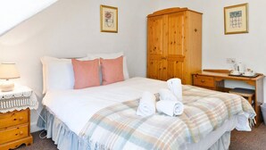 A bedroom with a bed, a wooden wardrobe, a bedside table, a lamp, and a framed picture on the wall. - Guestready - Links View (Edinburgh)