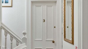 A white door with the number 3, a gold-framed mirror, and a red fire extinguisher on the wall. - Guestready - Links View (Edinburgh)
