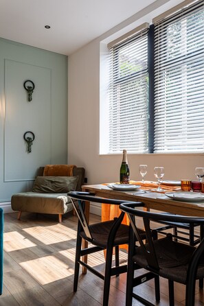 A dining area with a wooden table, chairs, a bottle of wine, and glasses. - Perfect Booking 2 Bed Flat Near Cabot Circus (Bristol)