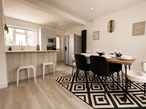 Une cuisine moderne avec un coin repas, des tabourets de bar blancs et un tapis à motifs géométriques.