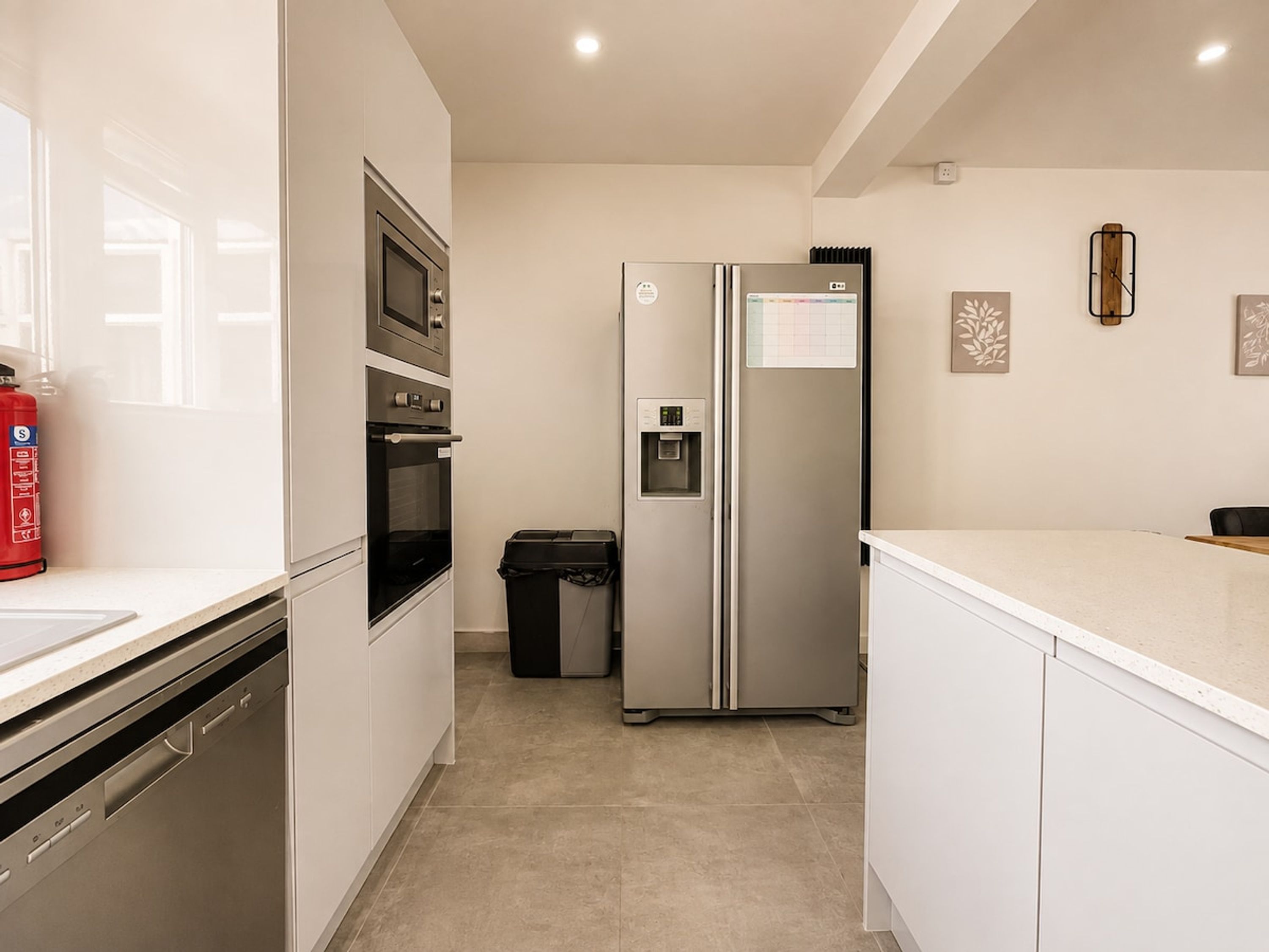 Een moderne keuken met roestvrijstalen apparatuur, een waterdispenser en een prullenbak.