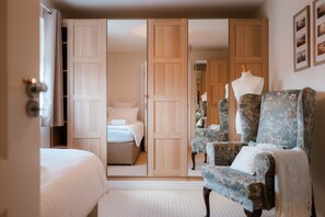 A hotel room with a bed, a chair, a wardrobe, and a mirror. - Perfect Booking Spacious 3-bed Home w Garden (Rochester)